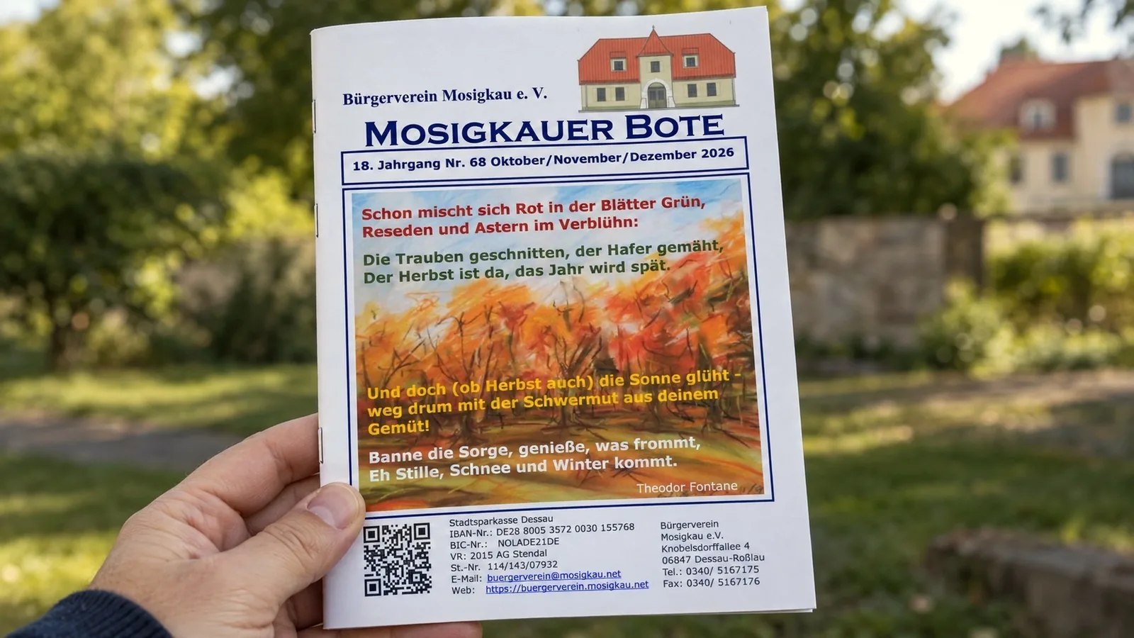 Hand hält die Herbstausgabe 2026 des Mosigkauer Boten, im Hintergrund das Schloss Mosigkau