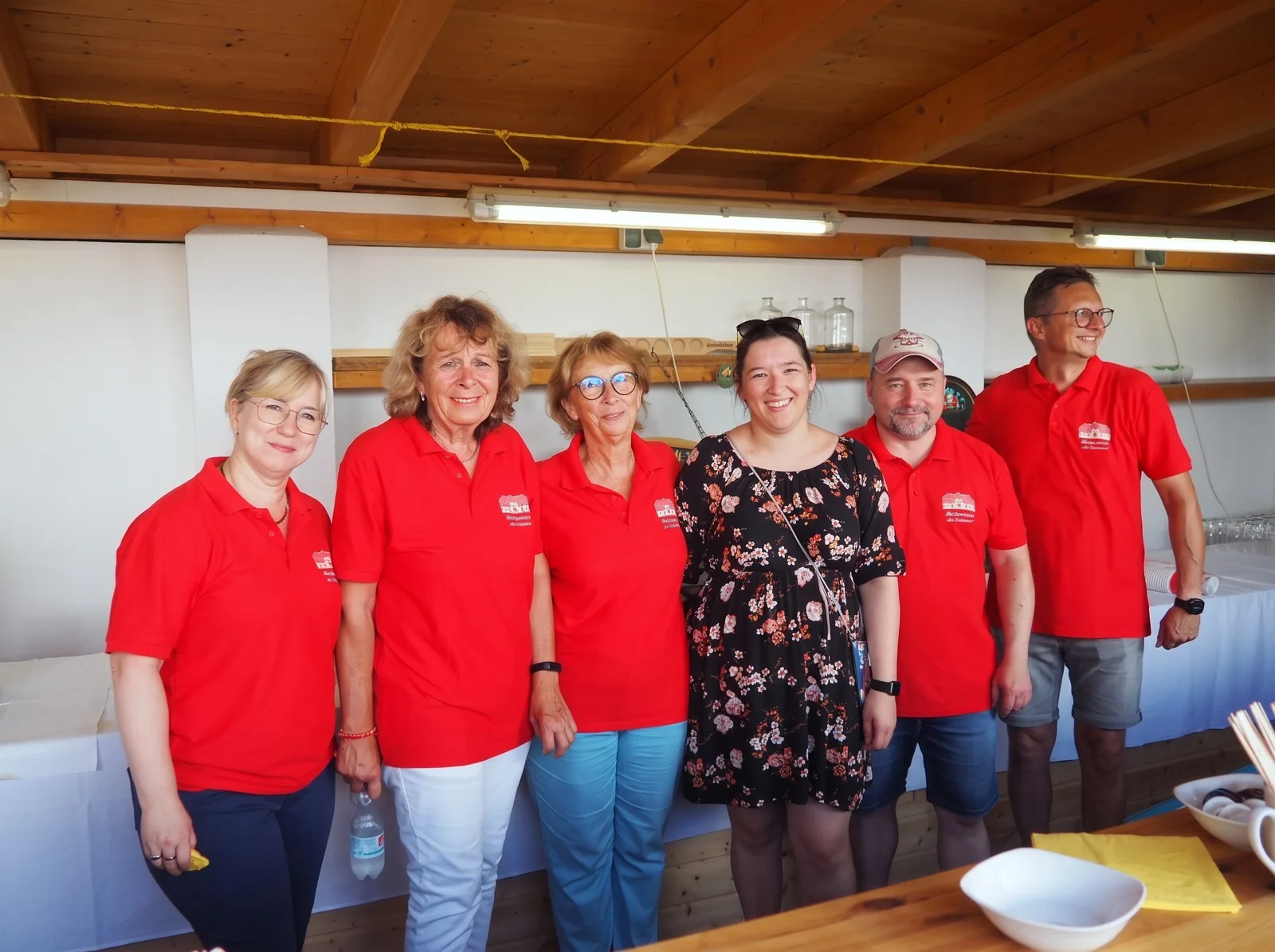 Helferinnen und Helfer des Bürgervereins in roten Vereinshemden unter dem Unterstand